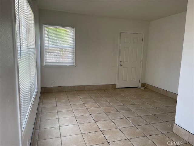 empty room with light tile patterned floors and baseboards