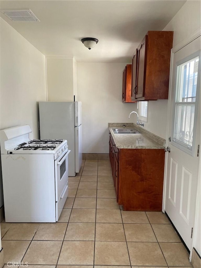 kitchen with light tile patterned floors, visible vents, white appliances, and a sink