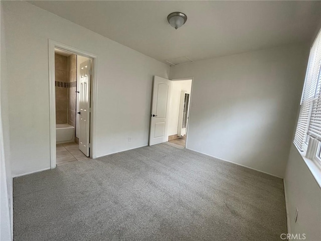 unfurnished bedroom featuring light colored carpet and ensuite bath