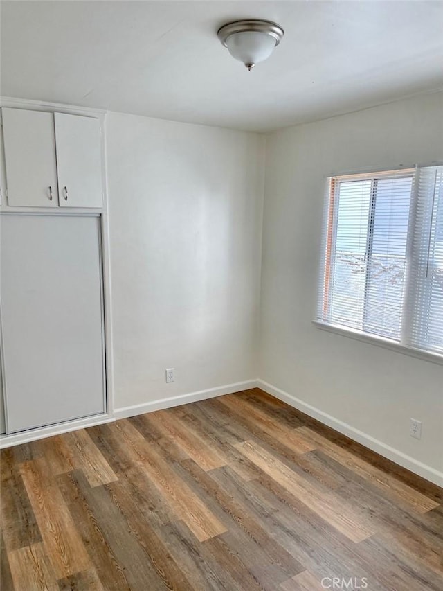 unfurnished bedroom featuring a closet, baseboards, and wood finished floors