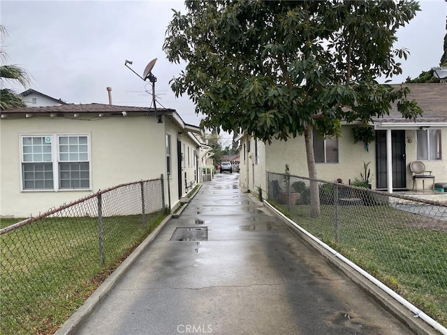 view of side of property featuring stucco siding, a lawn, and fence