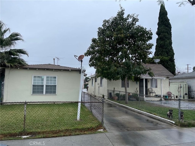 view of front of house featuring a front yard, a fenced front yard, driveway, and stucco siding