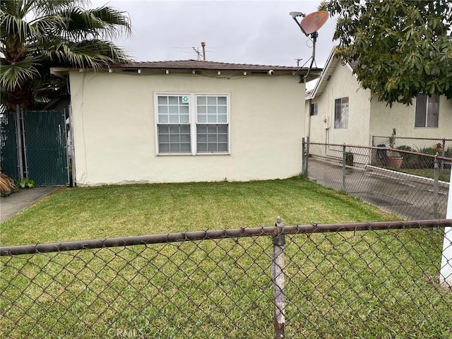 exterior space featuring stucco siding, a lawn, and fence