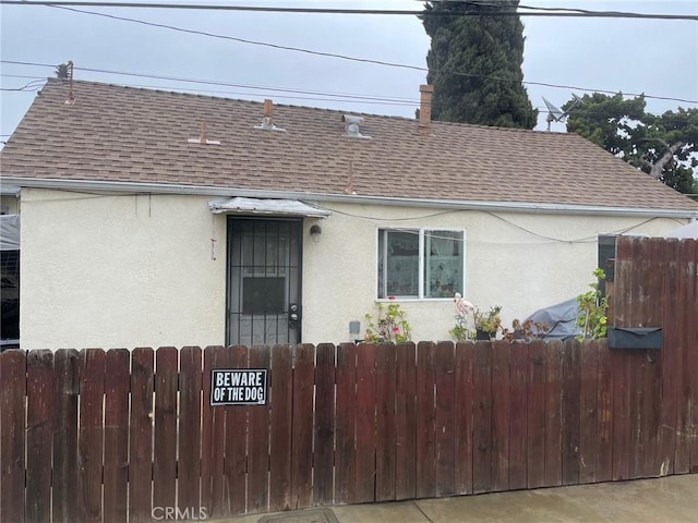 view of front of house with a fenced front yard, stucco siding, and a shingled roof