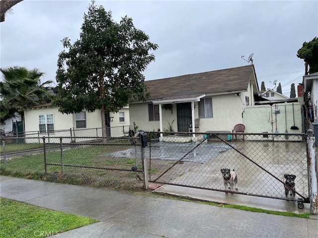 view of front of house with stucco siding, a fenced front yard, and a gate