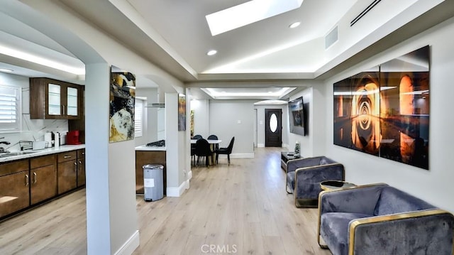 hallway featuring baseboards, visible vents, light wood-style flooring, recessed lighting, and a sink