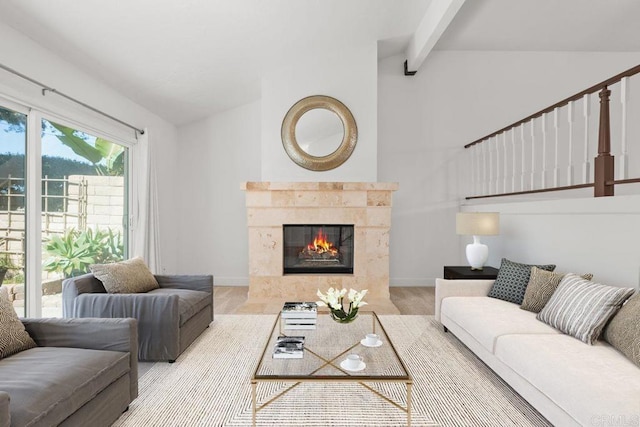 living area with vaulted ceiling with beams, a tile fireplace, and baseboards