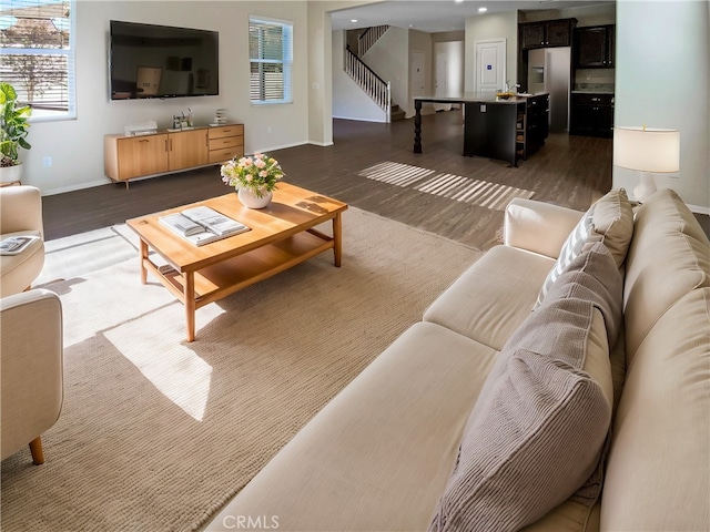 living room featuring baseboards, wood finished floors, and stairs