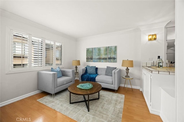 living area with baseboards, light wood-type flooring, and ornamental molding