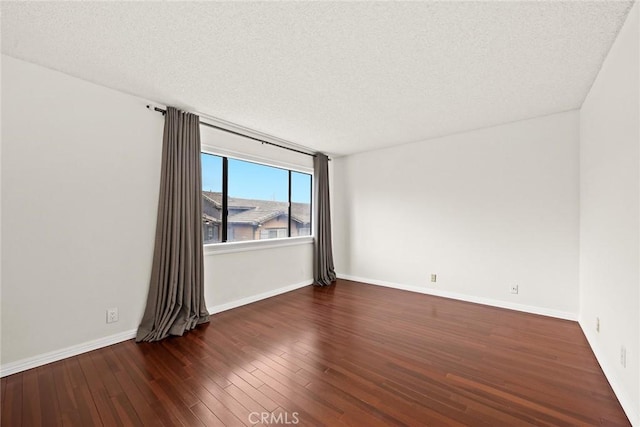 empty room with baseboards, a textured ceiling, and wood finished floors