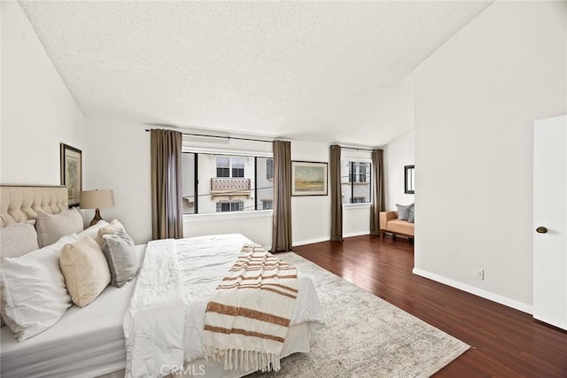 bedroom featuring a textured ceiling, baseboards, and dark wood-style flooring