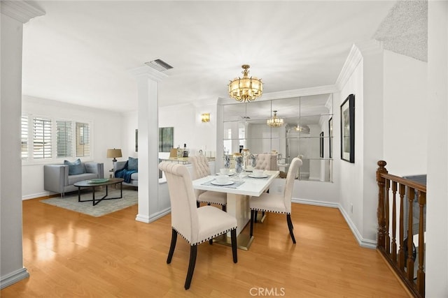 dining room with visible vents, a notable chandelier, ornamental molding, light wood finished floors, and decorative columns