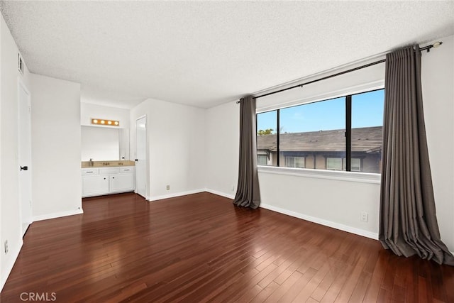 interior space with hardwood / wood-style flooring, visible vents, baseboards, and a textured ceiling