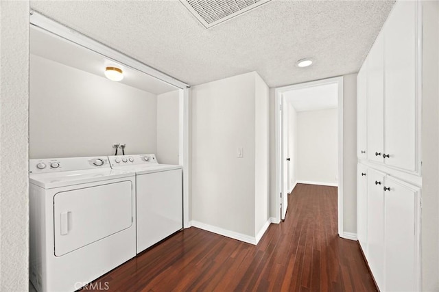 washroom featuring visible vents, baseboards, washing machine and dryer, dark wood-style floors, and a textured ceiling