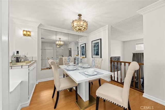 dining room with light wood-style floors, an inviting chandelier, and ornamental molding