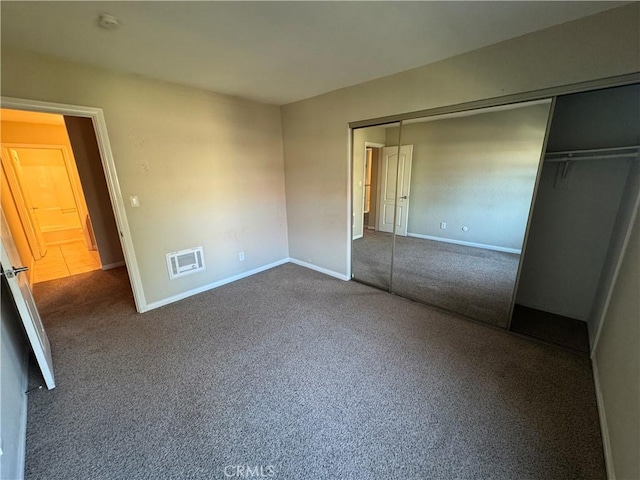 unfurnished bedroom with a closet, visible vents, baseboards, and carpet