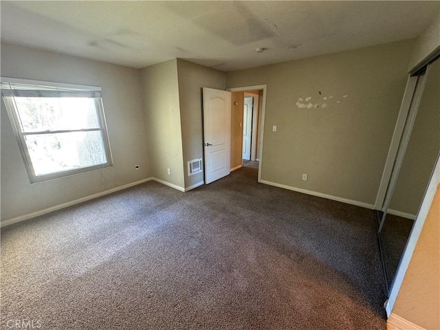 unfurnished bedroom with visible vents, baseboards, and dark colored carpet