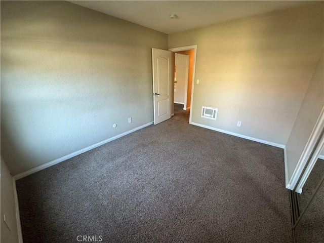 unfurnished bedroom featuring visible vents, dark carpet, and baseboards