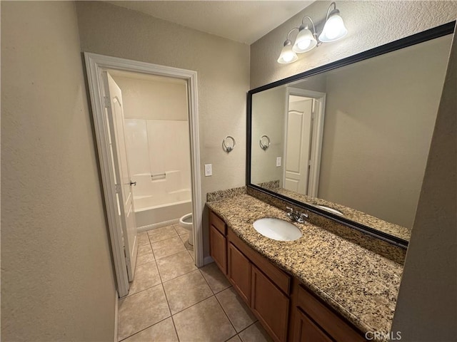 bathroom featuring tile patterned flooring, a washtub, toilet, a textured wall, and vanity