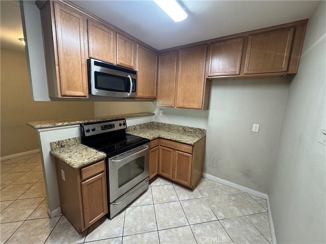 kitchen with light stone counters, stainless steel appliances, and light tile patterned flooring