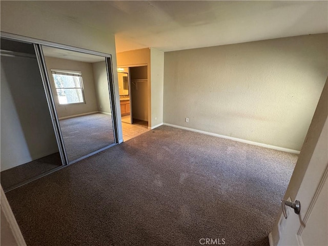 unfurnished bedroom featuring baseboards, carpet floors, and a closet