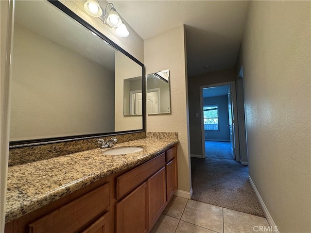 bathroom featuring tile patterned flooring, vanity, baseboards, and a textured wall