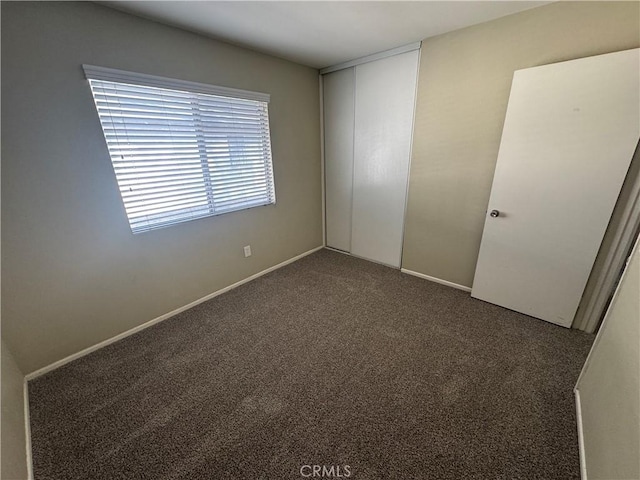 unfurnished bedroom with a closet, carpet flooring, and baseboards