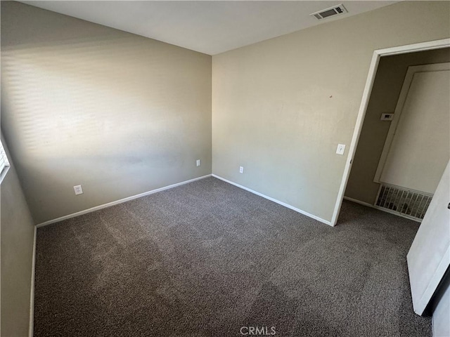 empty room with baseboards, visible vents, and dark colored carpet