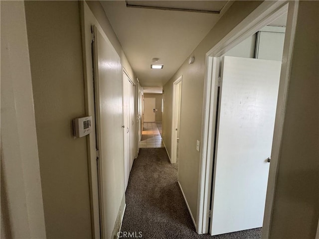 hall with baseboards and dark carpet