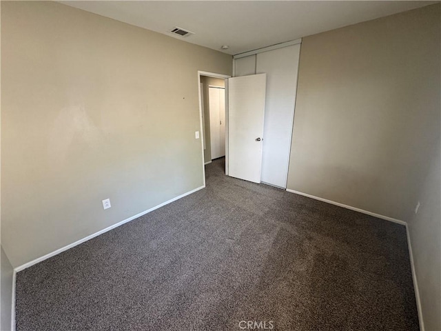 unfurnished bedroom with visible vents, baseboards, and dark carpet