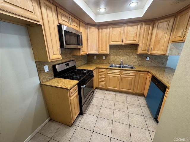 kitchen with light tile patterned floors, decorative backsplash, appliances with stainless steel finishes, a raised ceiling, and a sink