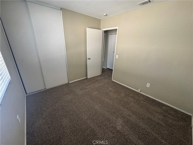 unfurnished bedroom featuring carpet, visible vents, a closet, and baseboards