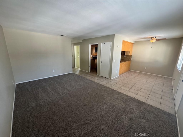 spare room featuring visible vents, light carpet, a ceiling fan, light tile patterned flooring, and baseboards