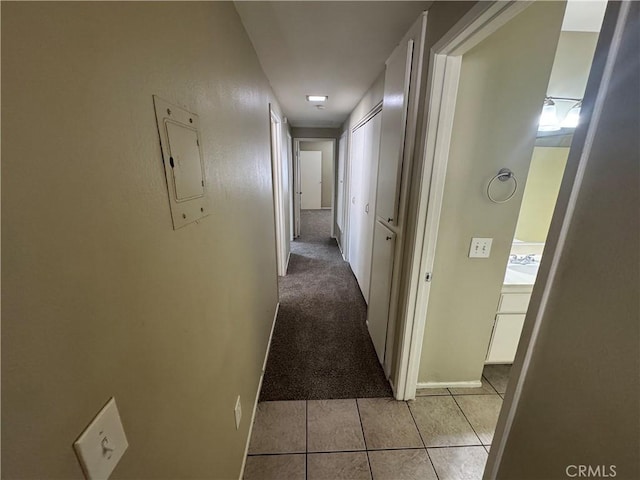 corridor with electric panel, light tile patterned floors, and light carpet