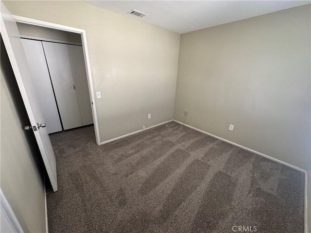 unfurnished bedroom featuring baseboards, visible vents, and dark carpet