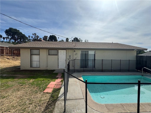 rear view of property with a fenced in pool, roof with shingles, stucco siding, and fence