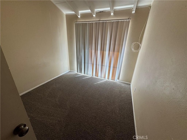 unfurnished room featuring beamed ceiling and carpet