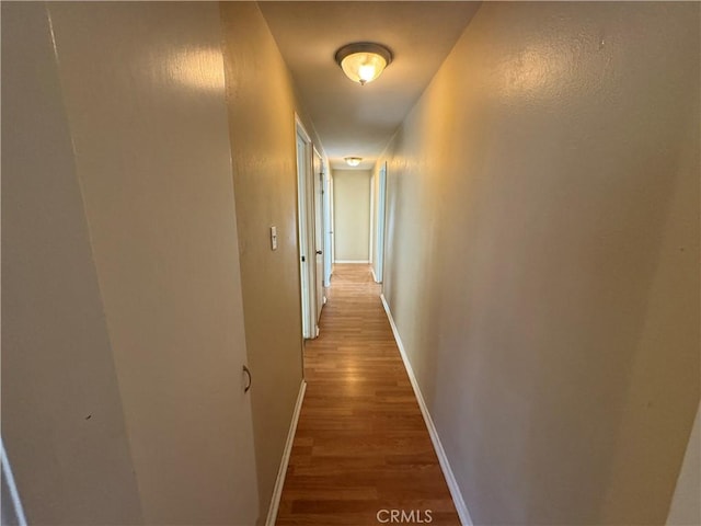 hallway featuring light wood-type flooring and baseboards