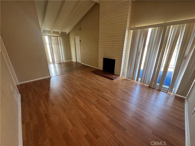 unfurnished living room with baseboards, beamed ceiling, a fireplace, wood finished floors, and high vaulted ceiling