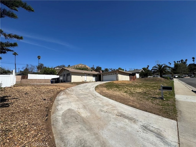 ranch-style house featuring an attached garage, driveway, and fence