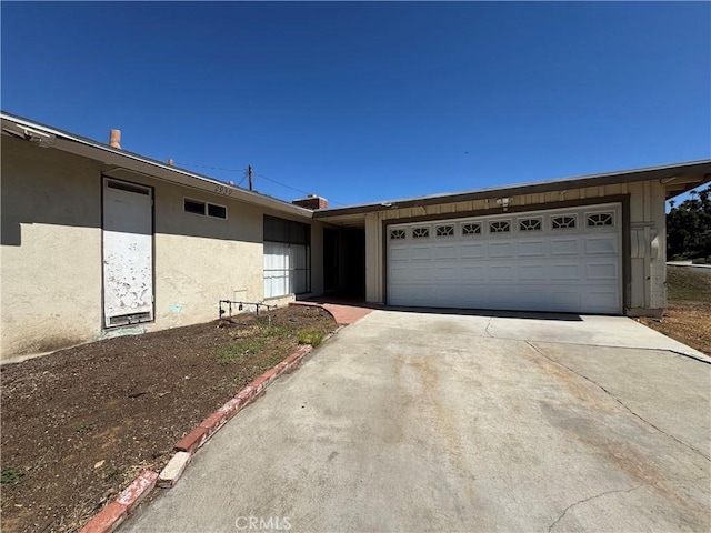 view of front of property featuring an attached garage, driveway, and stucco siding