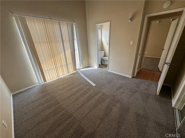 unfurnished bedroom with connected bathroom, baseboards, and carpet