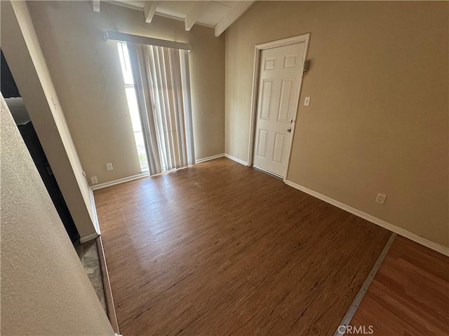 unfurnished room with baseboards, wood finished floors, and vaulted ceiling with beams