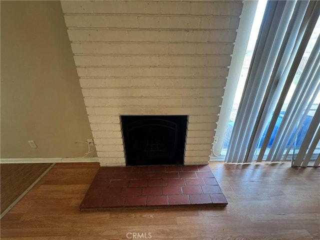 interior details with a brick fireplace, baseboards, and wood finished floors