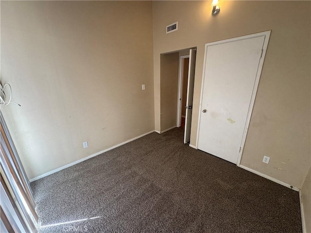 empty room with baseboards, visible vents, and dark carpet