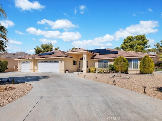 view of front of home with stucco siding, roof mounted solar panels, concrete driveway, and an attached garage