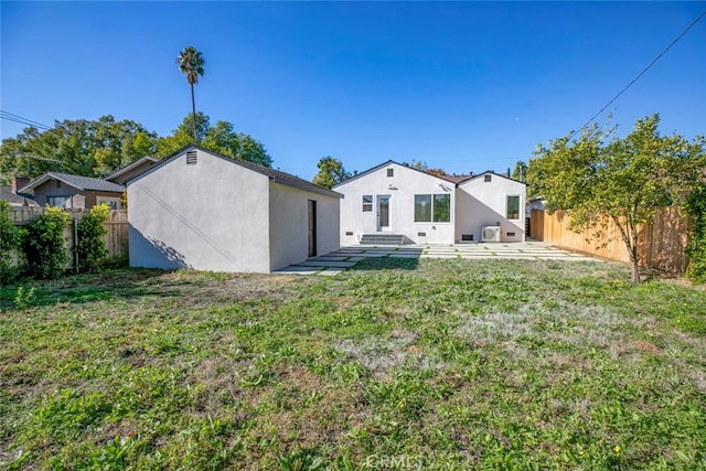 back of property featuring stucco siding, a lawn, and fence