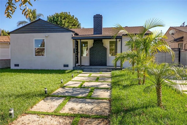 view of front of property featuring crawl space, a front yard, a chimney, and stucco siding