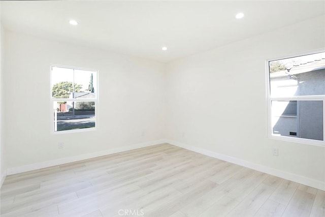 spare room featuring light wood finished floors, recessed lighting, and baseboards