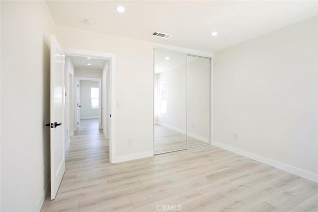 unfurnished bedroom featuring visible vents, baseboards, light wood-type flooring, recessed lighting, and a closet